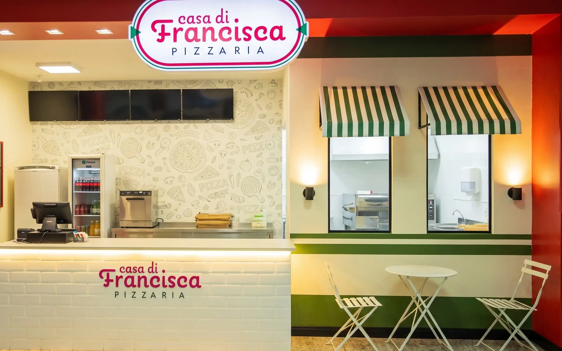 O balcão da pizzaria com a logo na parede e mesas na frente